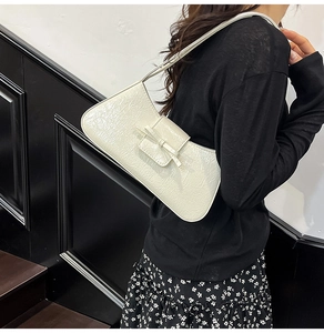 Close-up of creamy white pleated shoulder bag with delicate bow detail and slim strap
