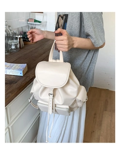 Detail of off-white PU leather backpack featuring drawstring closure and metal buckle strap
