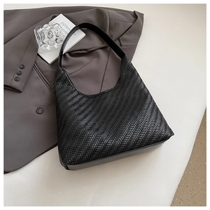 Detail of black woven texture hobo bag with smooth leather base on minimalist background