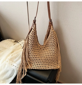 Detail of woven beach tote showing boho tassels and adjustable brown faux leather strap
