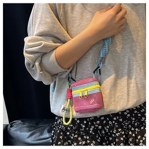 Detail of a mini mesh crossbody bag in rose pink with blue strap and colorful charms