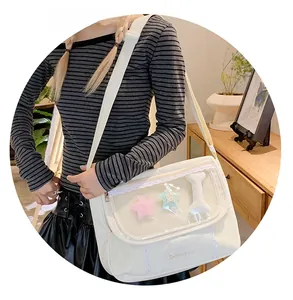 Close-up of white canvas messenger bag featuring a transparent PVC window with plush stars