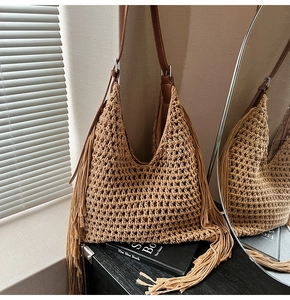 Detail of woven straw tote bag with long side tassels and brown leather shoulder strap