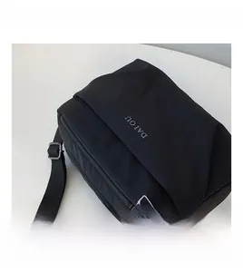 Detail of black nylon crossbody bag featuring adjustable strap and matte fabric texture