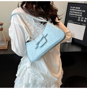 Detail of light blue wrinkled leather shoulder bag with a stylish ribbon bow ornament