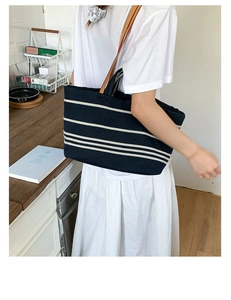 Detail of navy blue striped canvas tote bag with brown leather straps on shoulder