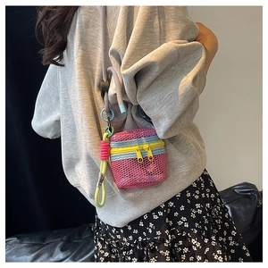 Detailed view of pink mesh mini bag with contrasting zippers and green woven strap
