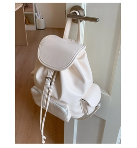 Detail view of cream soft leather drawstring backpack with multiple utility pockets
