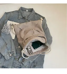 Detail view of khaki plaid drawstring bag interior showing daily essentials on denim jacket