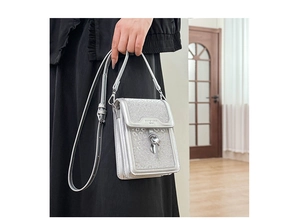 Detail of silver sequin mini crossbody bag featuring metallic twist lock and leather strap
