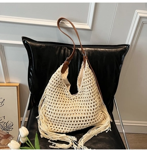 Detail of hand-woven cream tote bag with brown leather straps and tassels on a black chair