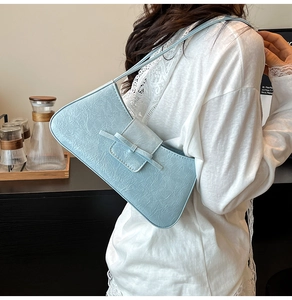 Detail of light blue shoulder bag with pleated leather texture and bow decoration