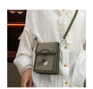 Detail of dark green leather and woven crossbody bag with metallic pendant