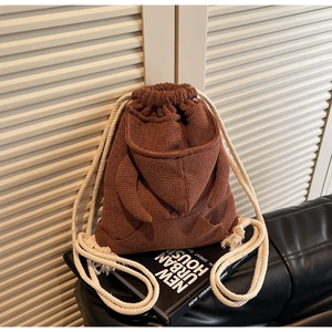 Detail of brown waffle-textured bucket bag with hoodie-style drawstring and decorative pockets