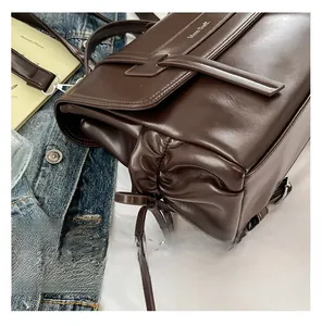 Close-up of deep brown faux leather shoulder bag with side drawstrings and logo detail