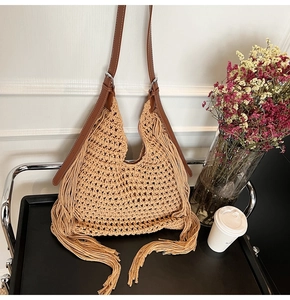 Close-up of woven hobo bag featuring long tassel details and adjustable leather strap