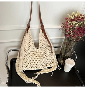 Detailed view of beige woven tote bag with long boho fringes and brown faux leather strap