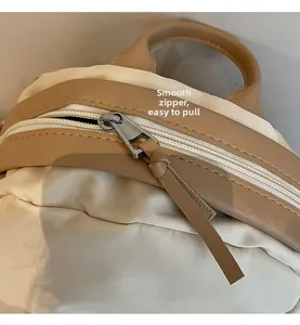 Detailed view of the smooth silver zipper and leather trim on a canvas commuter bag
