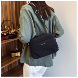 Detailed back view of a black nylon crossbody bag with white logo and adjustable strap