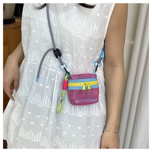 Detail of pink mesh crossbody bag with contrasting yellow zippers and woven strap