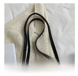 Détail de la poignée en cuir noir avec breloque sphérique dorée sur un sac transparent