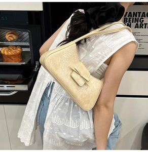 Detail view of cream underarm bag with pleated texture and a small bow decoration
