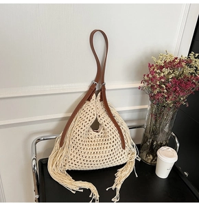 Close-up of handmade crochet tote with fringe tassels and adjustable brown leather strap
