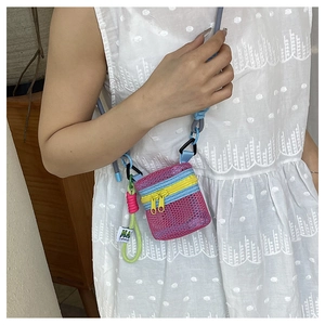 Detail of colorful mini mesh crossbody bag with pink body and yellow zipper on white dress