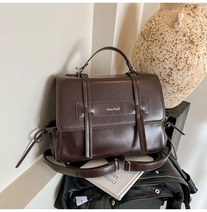 Detail of dark brown retro leather shoulder bag with buckle straps and brand lettering