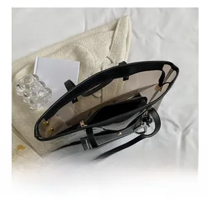 Vue de dessus du grand sac cabas transparent en PVC avec anses noires sur le lit