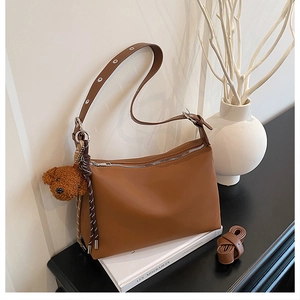 Vue détaillée du sac sous le bras marron mat avec bandoulière et porte-clés ours