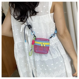 Detail view of mini mesh bag with bright yellow double zippers and colorful braided straps