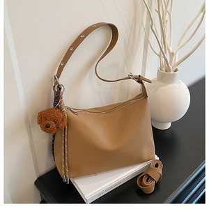Détail du sac sous le bras kaki avec bandoulière réglable et breloque ourson