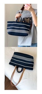 Detail of navy blue striped canvas tote with brown leather straps and dual handle design