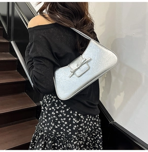 Detail of silver metallic shoulder bag with pleated texture and stylish bow buckle