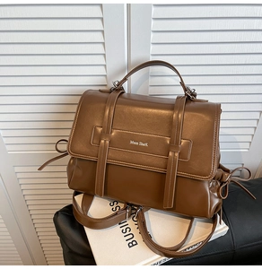 Close-up of brown soft leather shoulder bag featuring drawstring side and brand logo detail