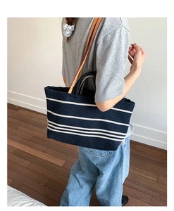 Detail of navy and white striped canvas tote bag with dual straps worn by a model