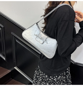 Detail of silver metallic shoulder bag with artistic pleats and stylish strap texture