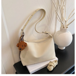 Gros plan d'un sac sous les bras crème avec un charmant ours en peluche sur une table