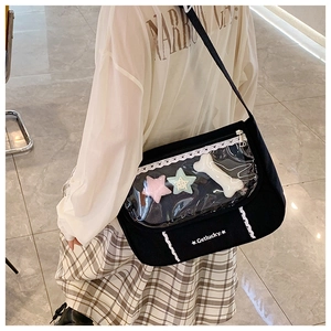 Detail view of black canvas ita bag with clear window, plush charms and lace trim