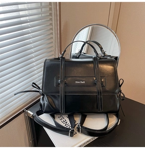 Detail of vintage black soft leather shoulder bag with sleek magnetic flap and bow decor