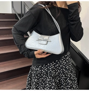 Detail view of metallic silver shoulder bag with bow decor and triple strap design