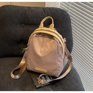 Detailed shot of a mini nylon backpack in taupe and cream with a silk-like finish