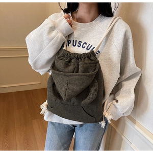 Detail of dark green corduroy drawstring bucket bag with unique hoodie pocket design