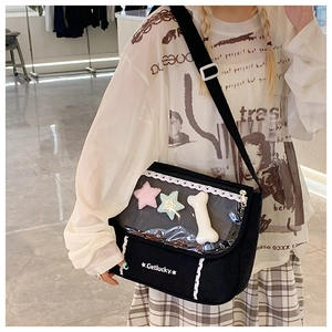 Detail of black canvas messenger bag with a lace-trimmed clear window for plush ornaments