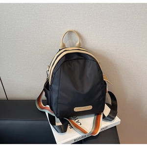 Detail of trendy black nylon backpack with beige PU trim and colorful striped shoulder straps