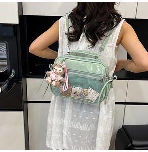 Detail view of mint green PVC transparent ita bag with plush rabbit charm and straps
