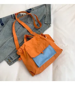 Détail du sac fourre-tout en nylon imperméable orange avec poche contrastée bleue