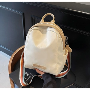 Detail of a beige mini backpack with colorful striped canvas strap and leather brand logo
