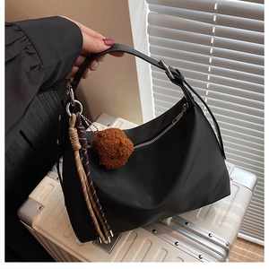 Détail du sac sous l'aisselle noir imperméable avec breloque ours sur valise